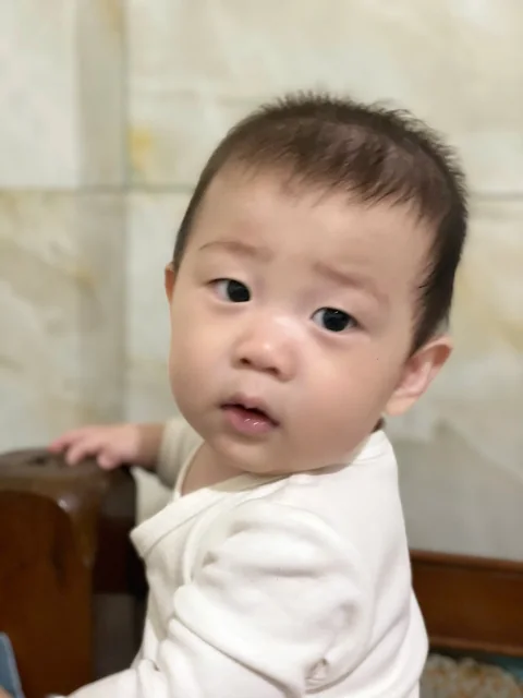 Bé Tú Tài mặc áo trắng và nhìn về phía máy ảnh