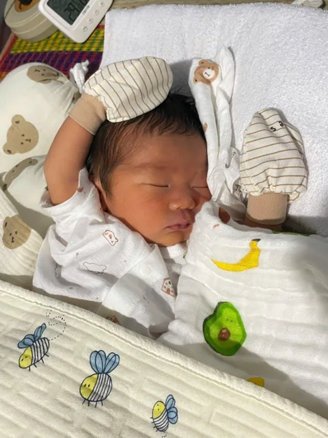 Bé Tú Tài ngủ ngoan, đôi tay đeo bao tay đặt bên đầu